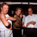 Sue checks her bra strap. Sheila and John look on