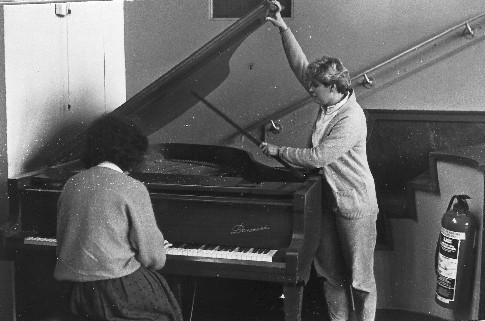 Liz plays piano as Anna puts the lid up from Learning Black-and-White Photography, Brockenhurst College, Hampshire - 10th March 1985