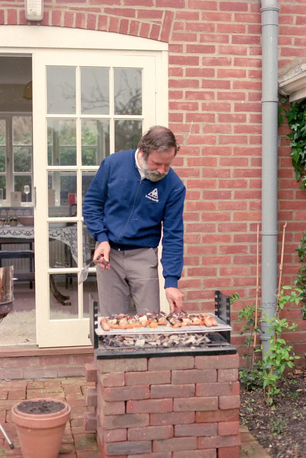 Ando pokes some barbeque food, from Nosher's 18th Birthday, Barton on Sea, Hampshire - 26th May 1985