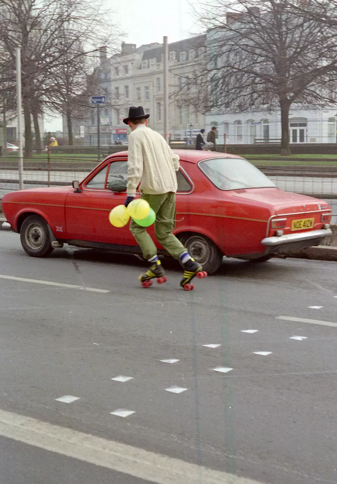 A dude on rollerskates chases down a Ford Escort, from Uni: PPSU "Jazz" RAG Street Parade, Plymouth, Devon - 17th February 1986