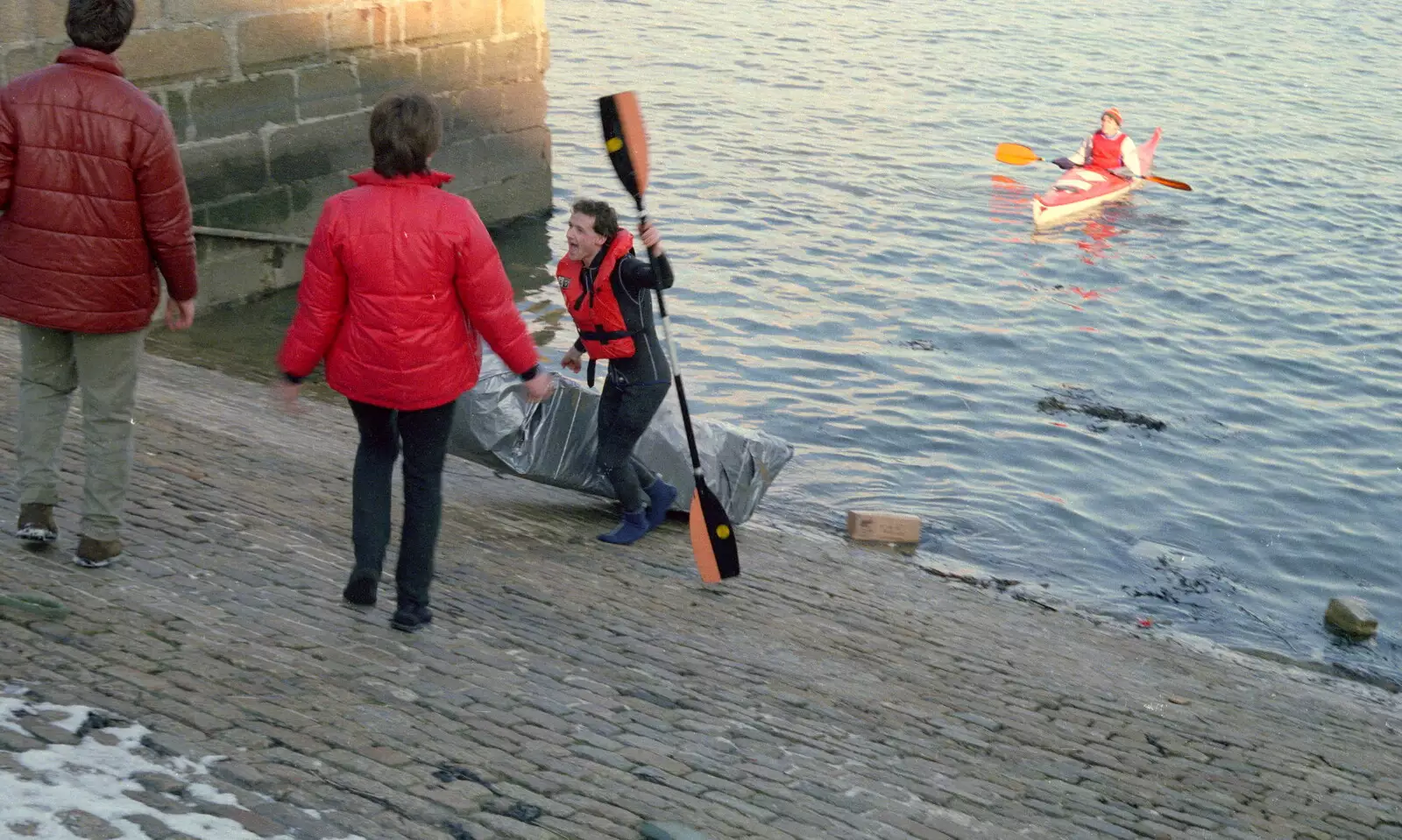 A rafter escapes the frigid water, from Uni: Canoe Society RAG Raft Madness, Plymouth Sound - 1st March 1986