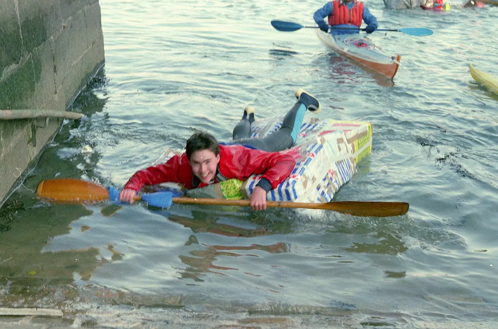 Paddling in on a raft made of Tesco carrier bags, from Uni: Canoe Society RAG Raft Madness, Plymouth Sound - 1st March 1986