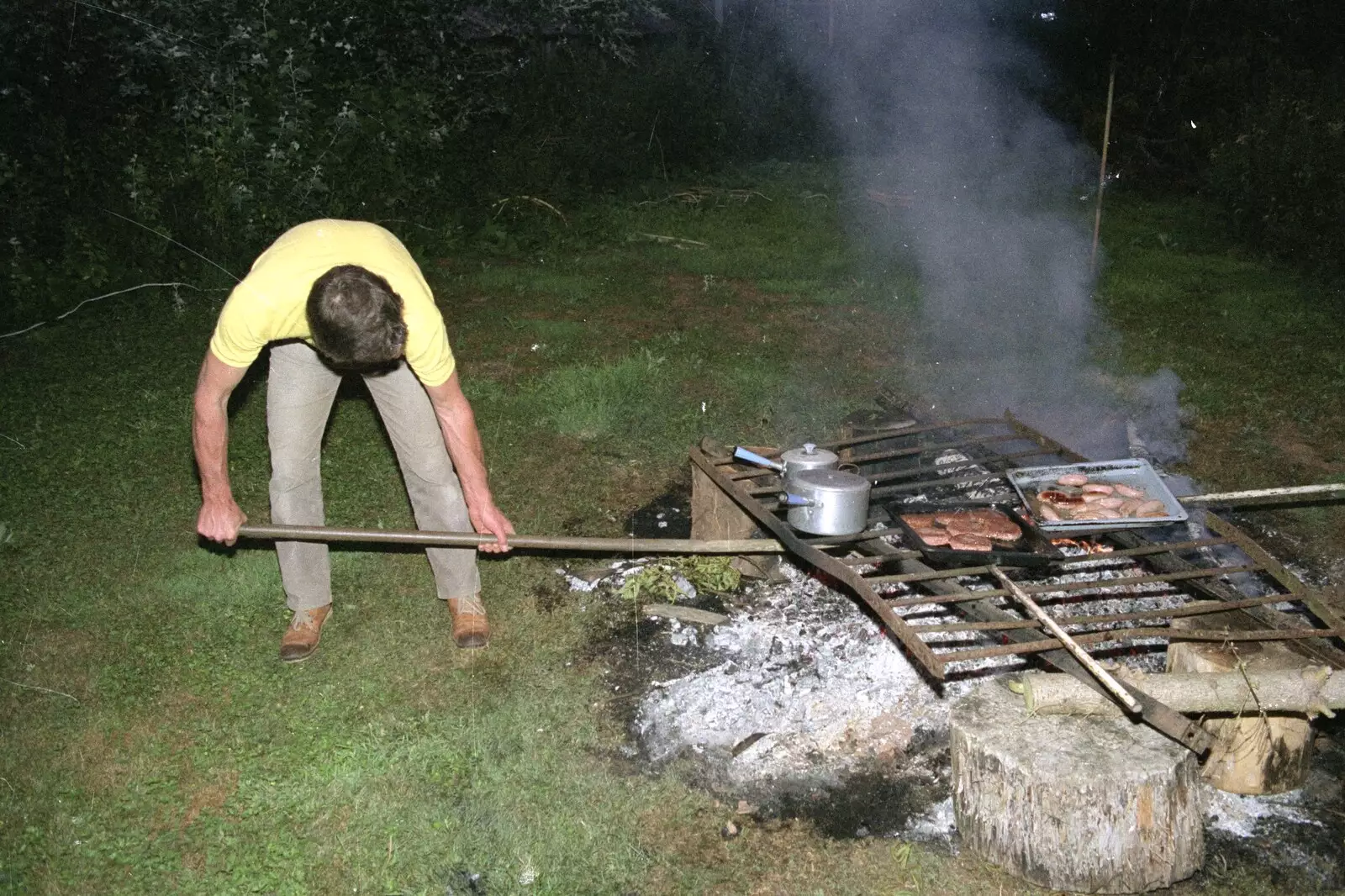 Geoff pokes the barbeque with a long stick, from Sue's Fire Dance, Stuston, Suffolk - 21st July 1990