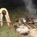 Geoff attends to the embers whilst sausages cook above