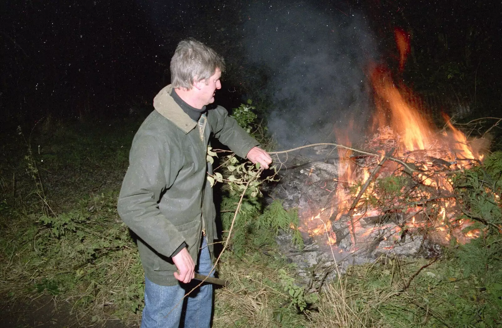 Geoff pokes the fire with a stick, from Bonfire Night and Printec at the Stoke Ash White Horse, Suffolk - 5th November 1991