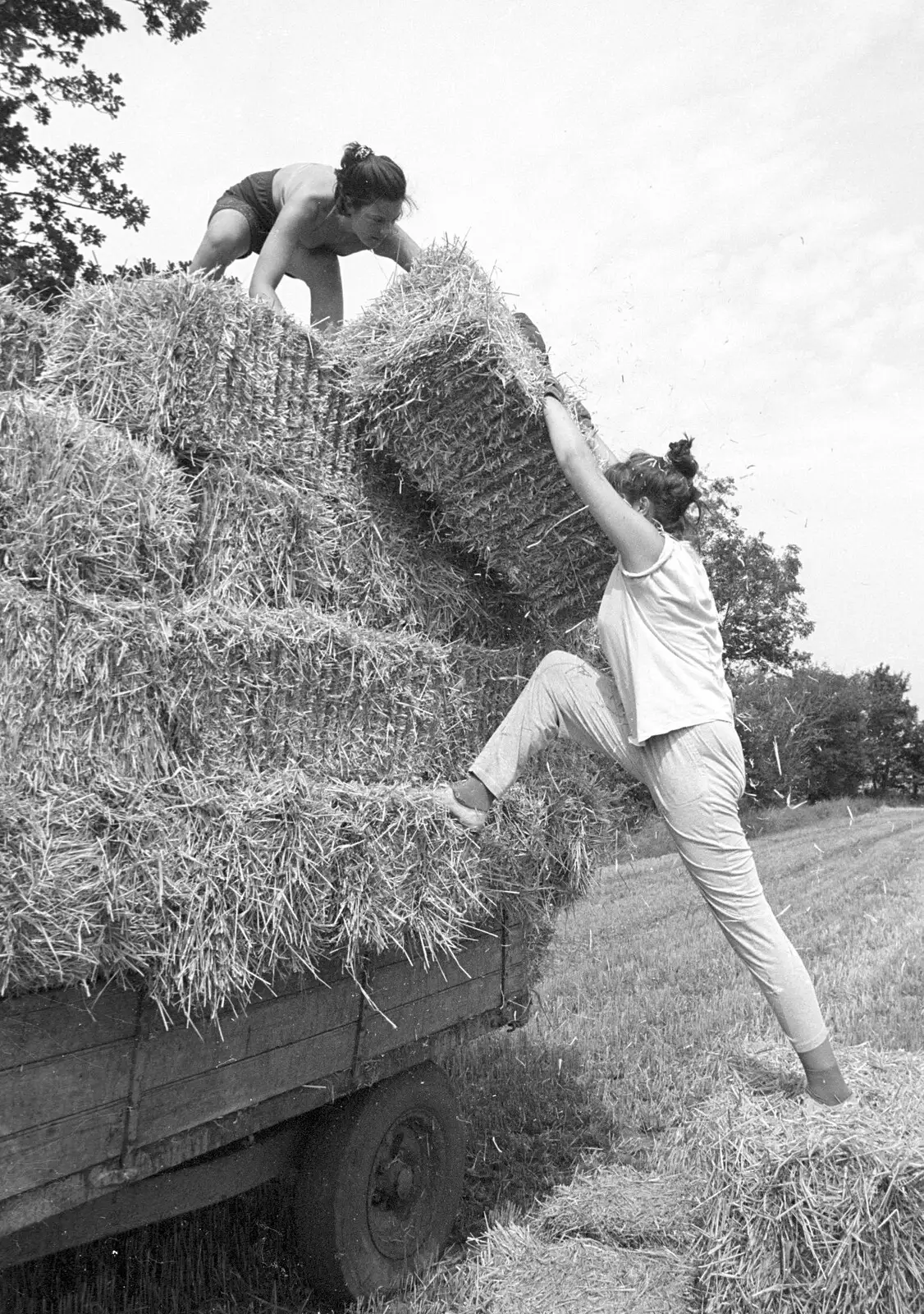 Rachel half-climbs up to shift a bale, from Working on the Harvest, Tibenham, Norfolk - 11th August 1992