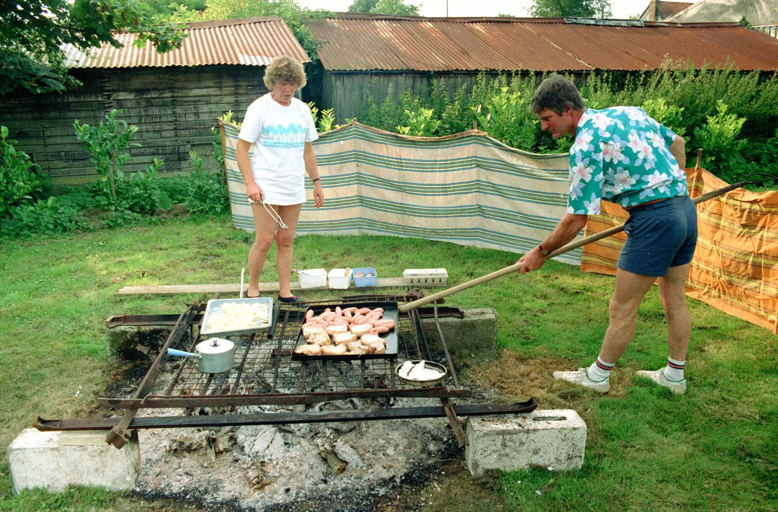 Geoff pokes the massive barbeque pit, from A Geoff and Brenda Barbeque, Stuston, Suffolk - 3rd April 1994