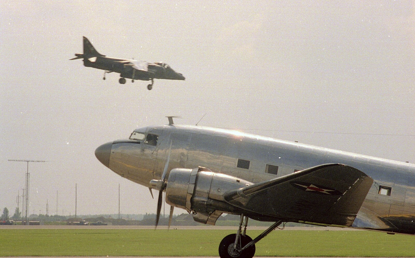 The Harrier flies past a taxiing C-47 from The Mildenhall Air Fete, Mildenhall, Suffolk - 29th May 1994