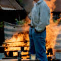 Bernie surveys pallets burning on the barbeque pit