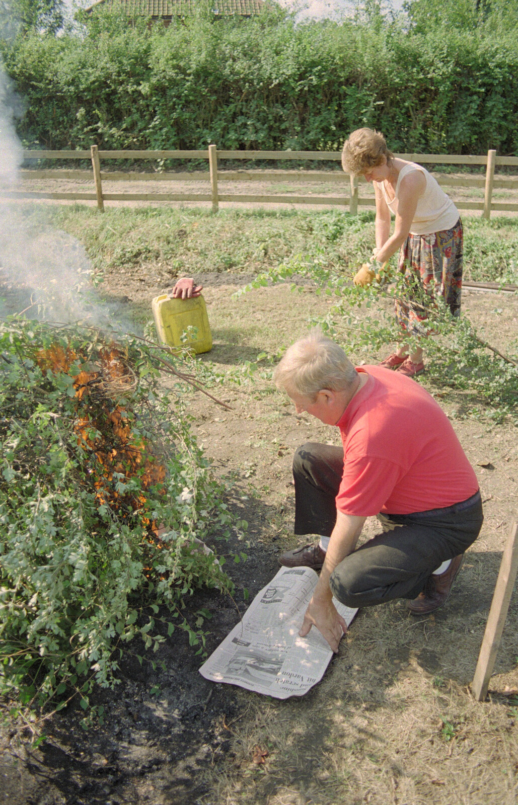 Tony adds more newspaper to the bonfire from Tony and Janet's Building Plot, and the Red Arrows, Eye, Suffolk - 22nd July 1998
