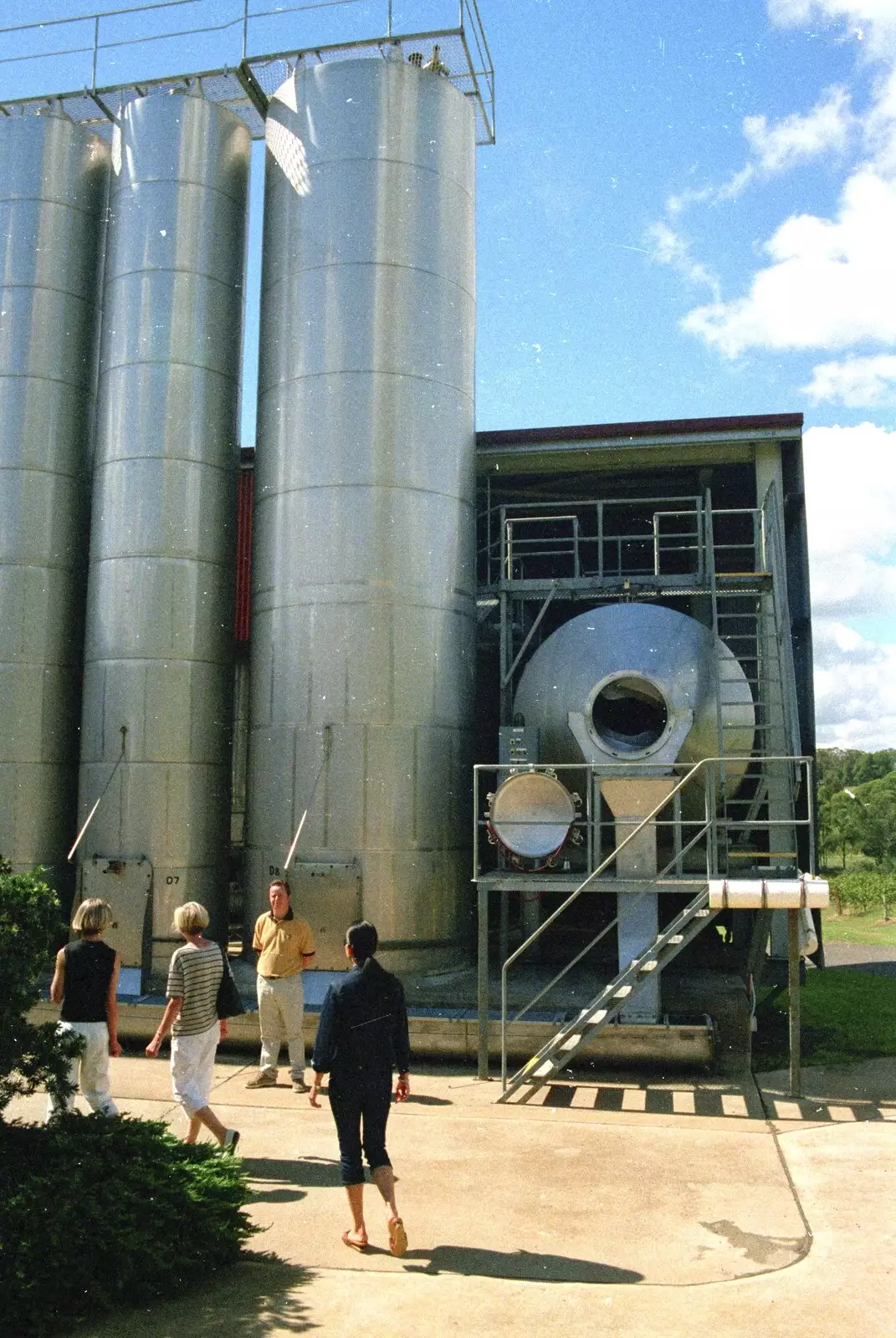 The tour guide stands by some storage tanks, from A Trip to the Zoo, Sydney, Australia - 7th April 2000