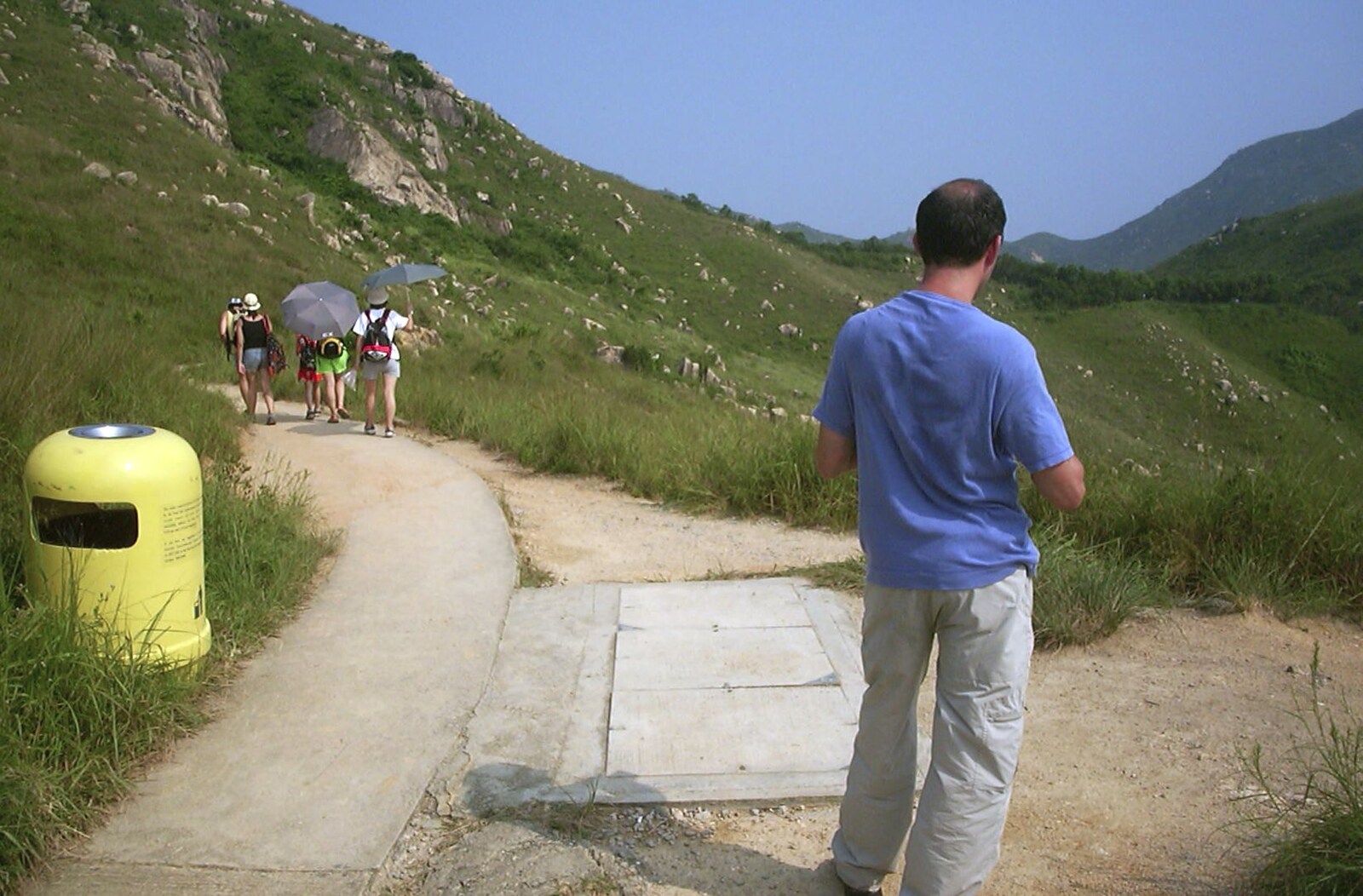 Lamma Island, Hong Kong, China - 20th August 2001: Walkers with umbrellas pass us by