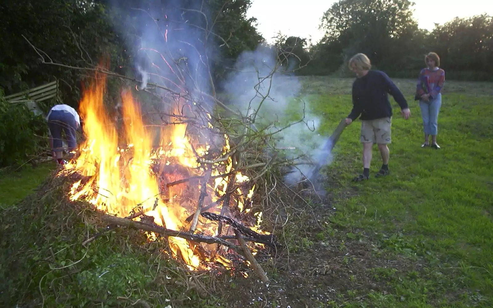 Marc hurls a plank of wood onto the fire, from DH's BSCC Barbeque, The Old Post Office, Brome, Suffolk - 7th July 2002