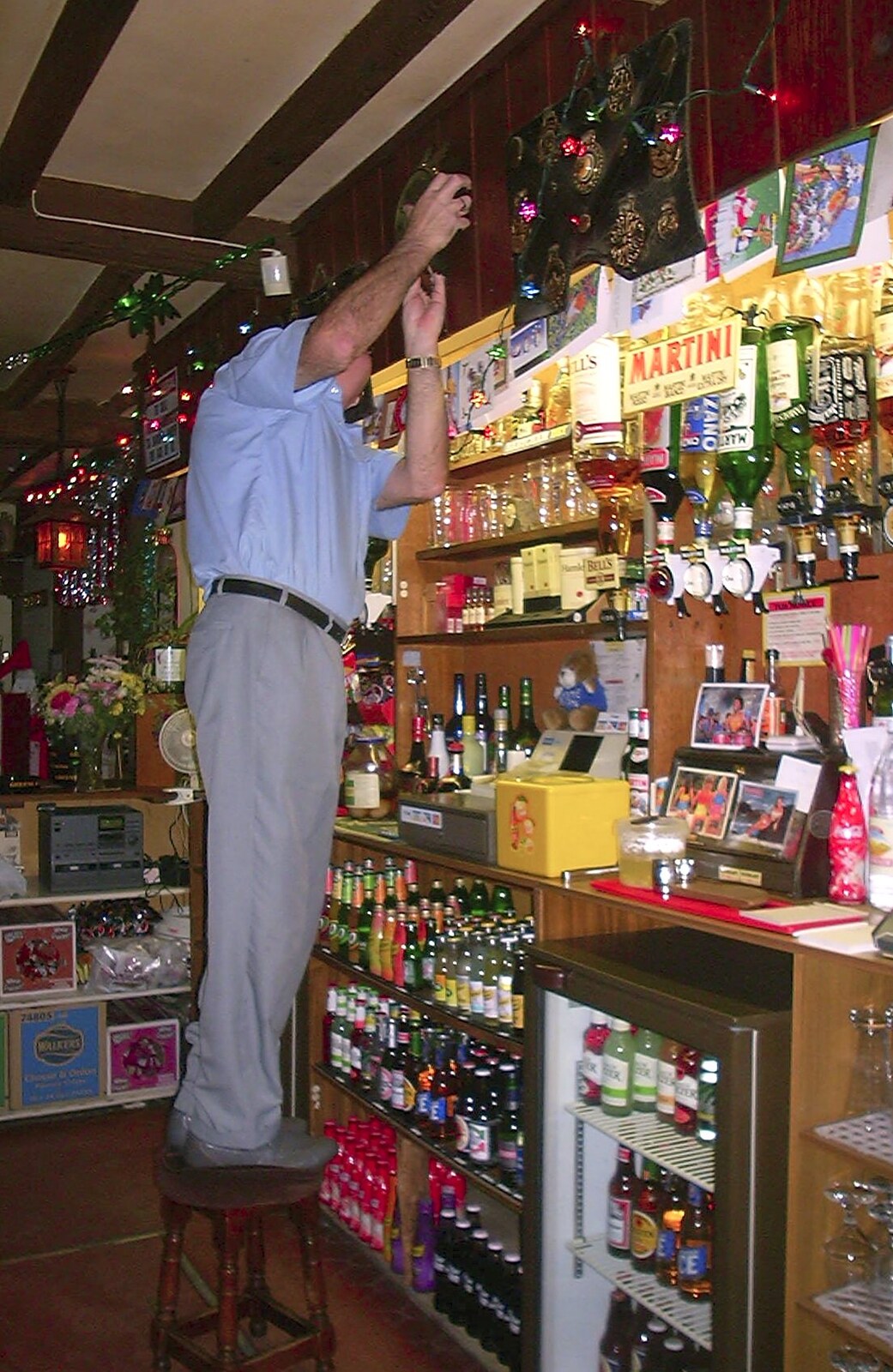 Alan fiddles around behind the bar from Christmas Day at Nosher's, Brome, Suffolk - 25th December 2002