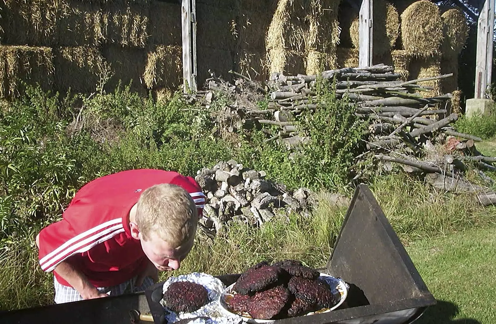 Bill blows on some singed burgers, from A Rabbit Barbeque, Dairy Farm, Thrandeston - 14th September 2003