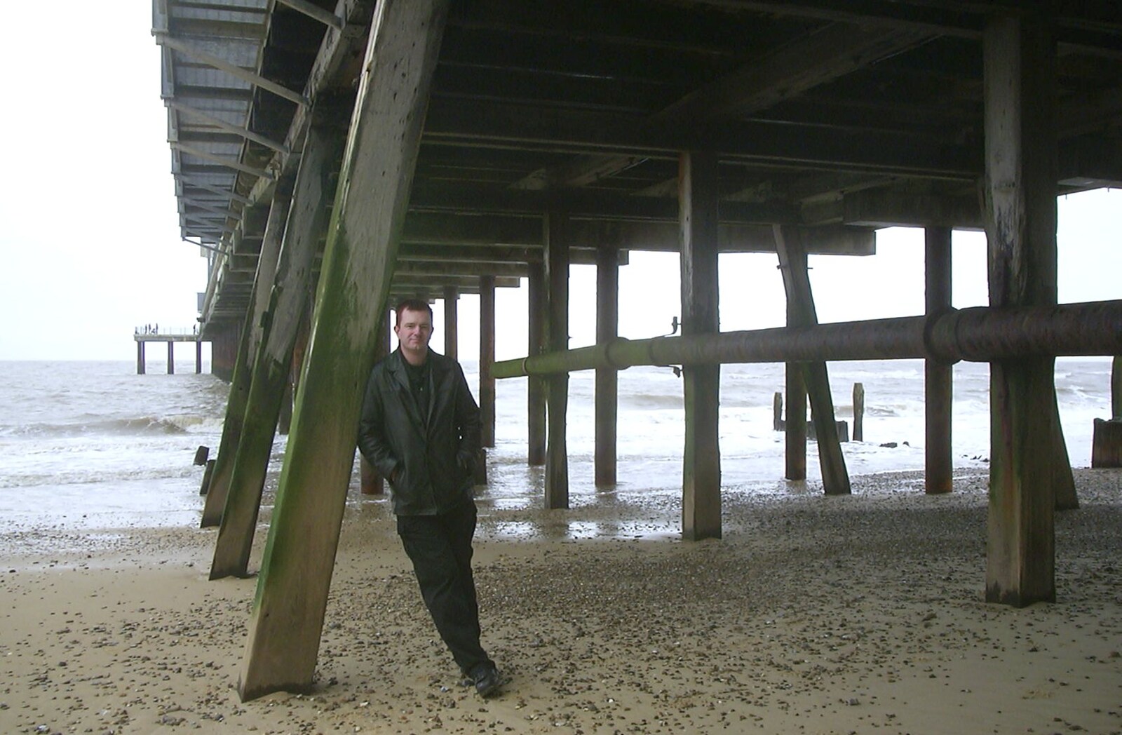 Nosher leans against the pier supports from Moping in Southwold, Suffolk - 3rd April 2004