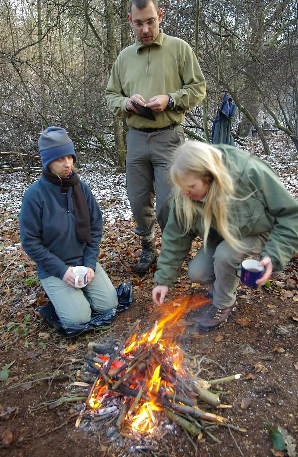 Our camp fire gets going as Annette inspects, from Walk Like a Shadow: A Day With Ray Mears, Ashdown Forest, East Sussex - 29th December 2005