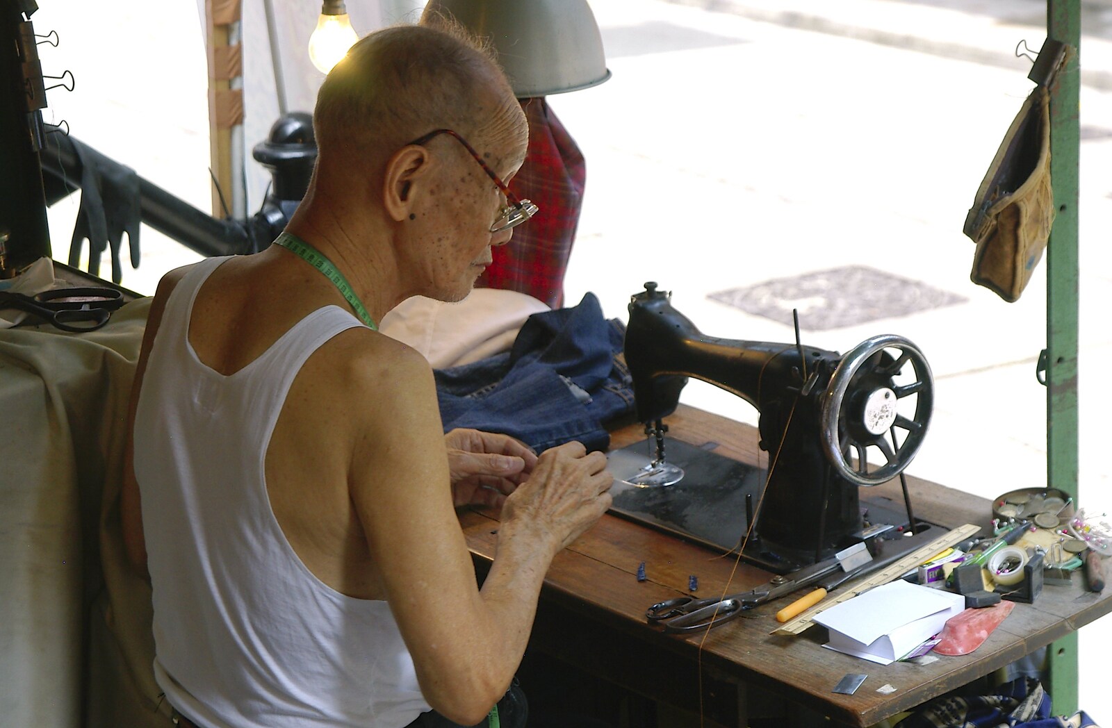An old dude works a vintage Singer sewing machine from Wan Chai and Central, Hong Kong, China - 2nd October 2006