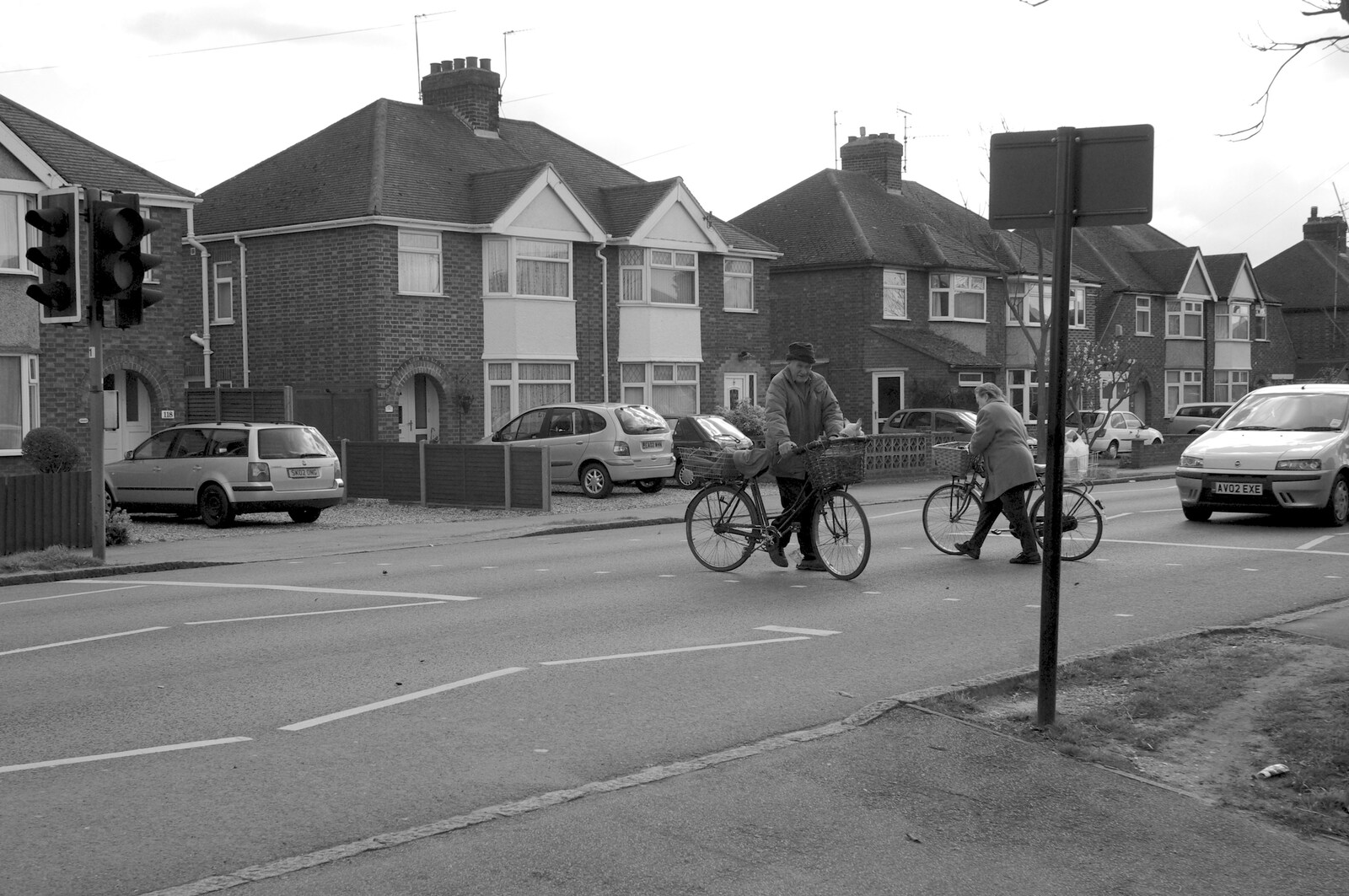 A couple of cyclists cross the road from The Derelict Salam Newsagents, Perne Road, Cambridge - 18th March 2007