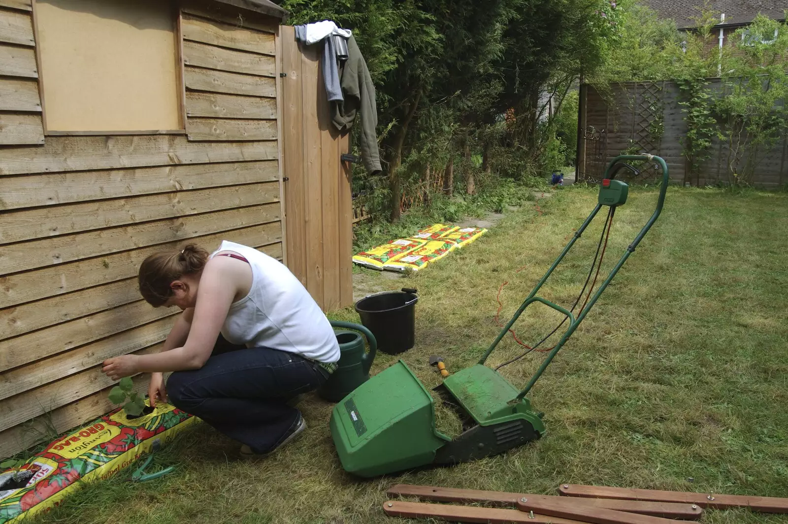 Isobel plants a cucumber in the garden of the flat, from Science Park Demolition, Bjarne Stroustrup, and Taptu/Qualcomm Miscellany, Cambridge - 29th April 2007