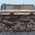 An old Winnebago sits on the clifftop, whilst some of the road falls in to the sea