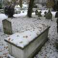 Orange leaves scatter on a snowy grave
