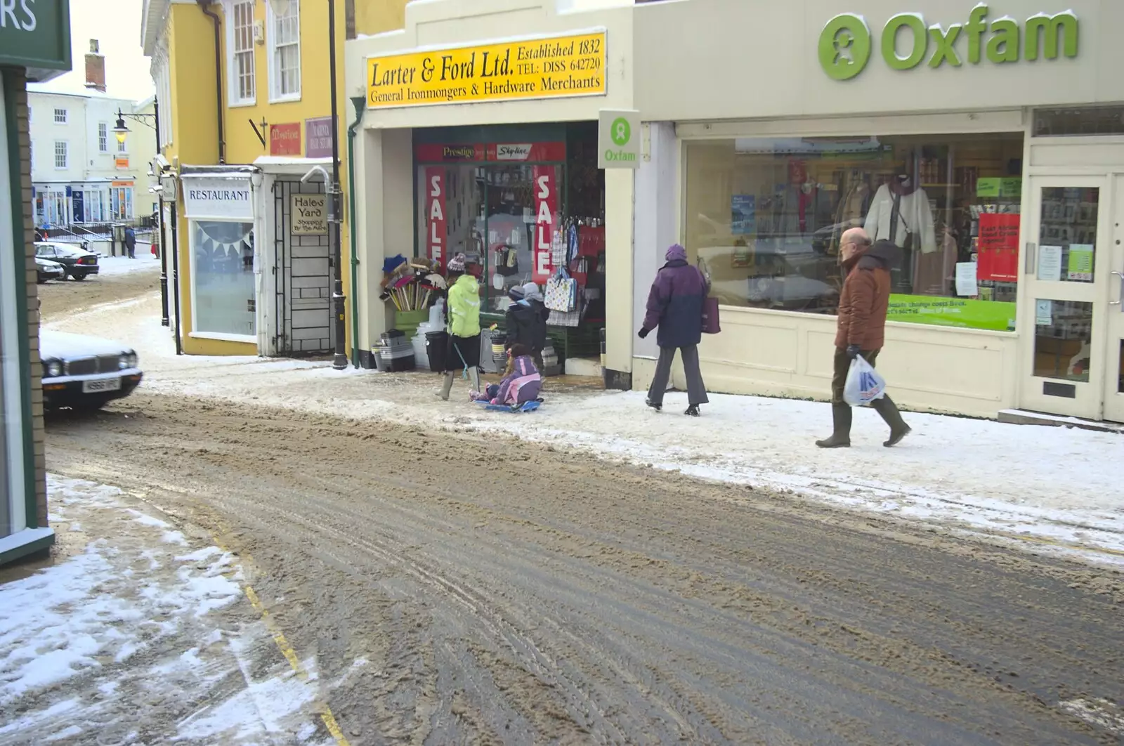 A child sleds past Larter and Ford, from A Snowy Miscellany, Diss, Norfolk - 9th January 2010