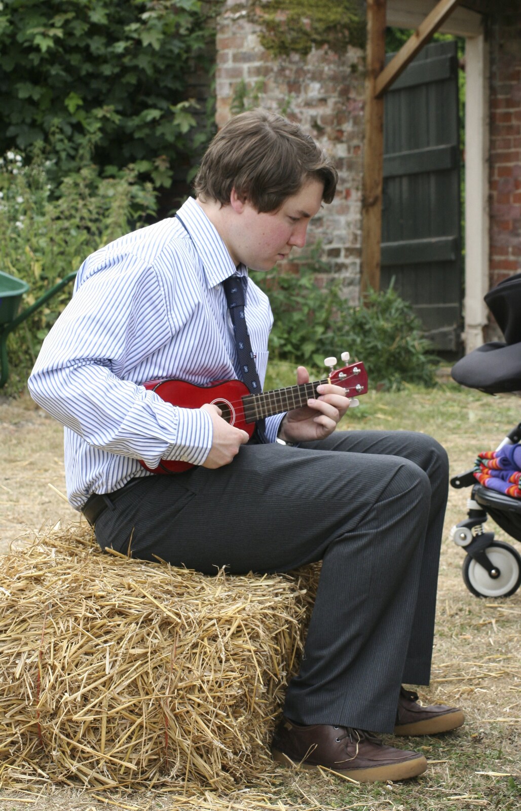 Eoghan plays ukulele on a straw bale from Nosher and Isobel's Wedding, Brome, Suffolk - 3rd July 2010