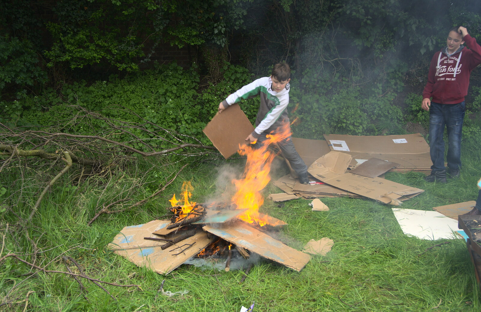 A boy fans the bonfire from Demolishing The 1st Eye Scout Hut, Wellington Road, Eye, Suffolk - 11th May 2013