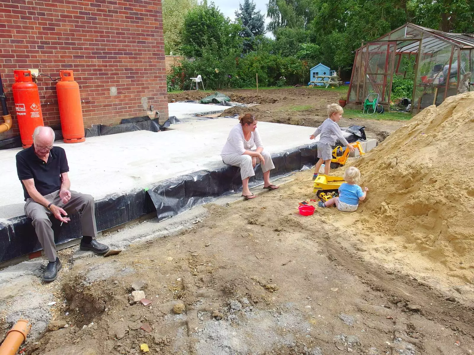 Grandad sits down on the new footings, from A Giant Sand Pile, and a Walk at Thornham, Suffolk - 17th August 2013