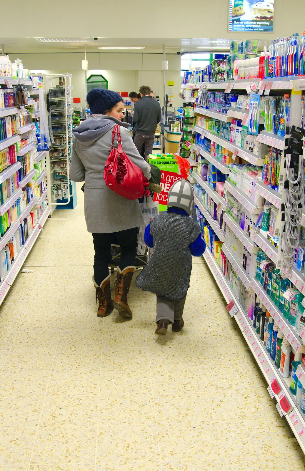 Isobel scopes for snacks in Framlingham's Co-Op, from A Trip to Framlingham Castle, Framlingham, Suffolk - 16th February 2014