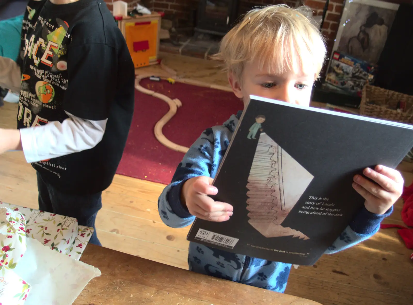 Harry opens up a Christmas book, from Christmas Day at the Swan Inn, Brome, Suffolk - 25th December 2014