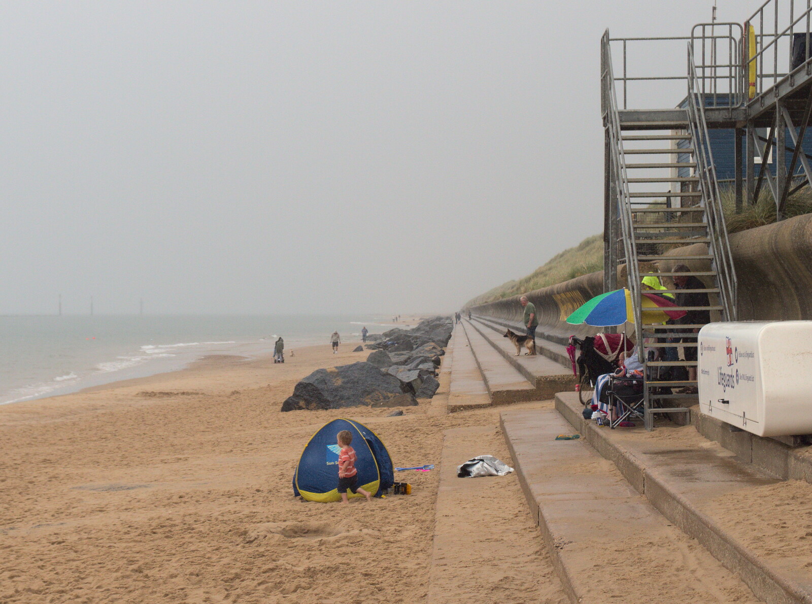 Brave beach-goers brave the rain under umbrellas from A Wet Day at the Beach, Sea Palling, Norfolk - 16th July 2017