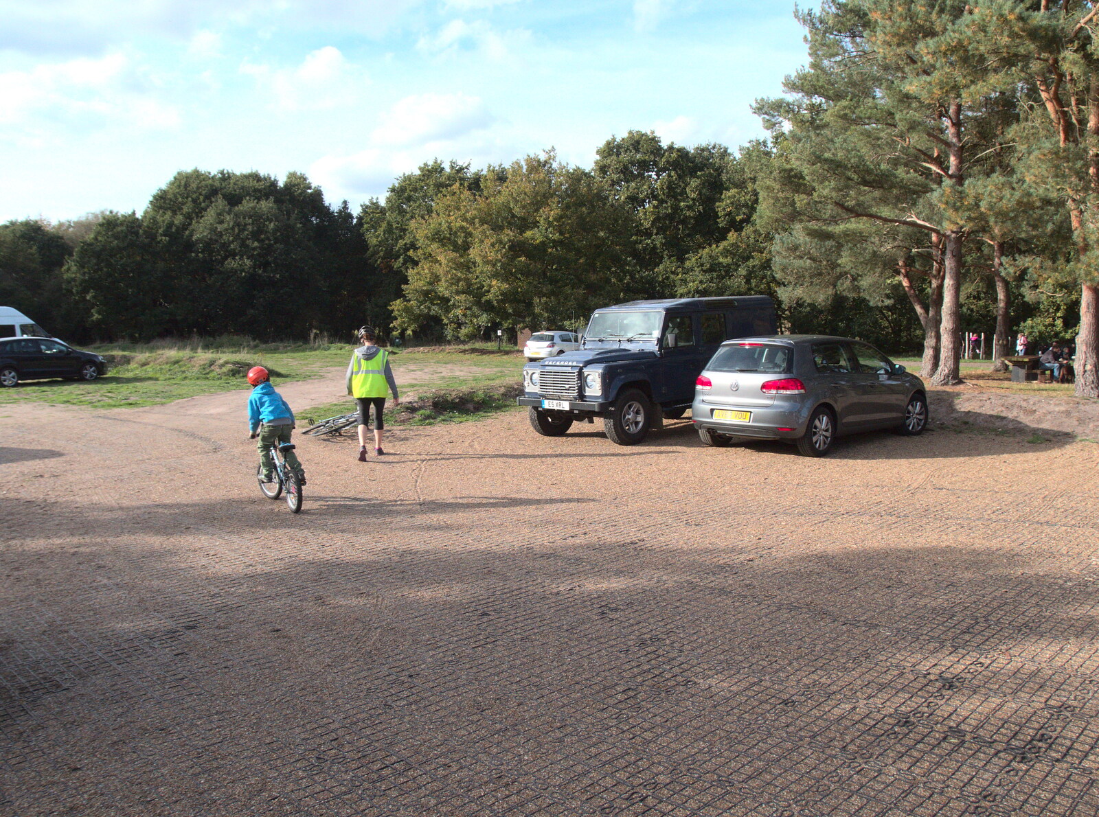 Harry cycles off across the car park from Evidence of Autumn: Geocaching on Knettishall Heath, Suffolk - 7th October 2018