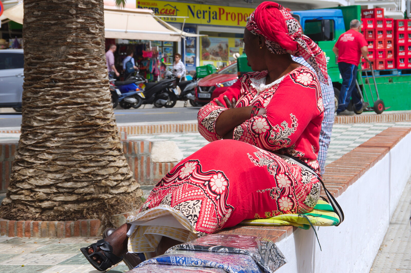 An African woman waits to sell blankets from Torrecilla Beach and the Nerja Museum, Andalusia, Spain - 17th April 2019