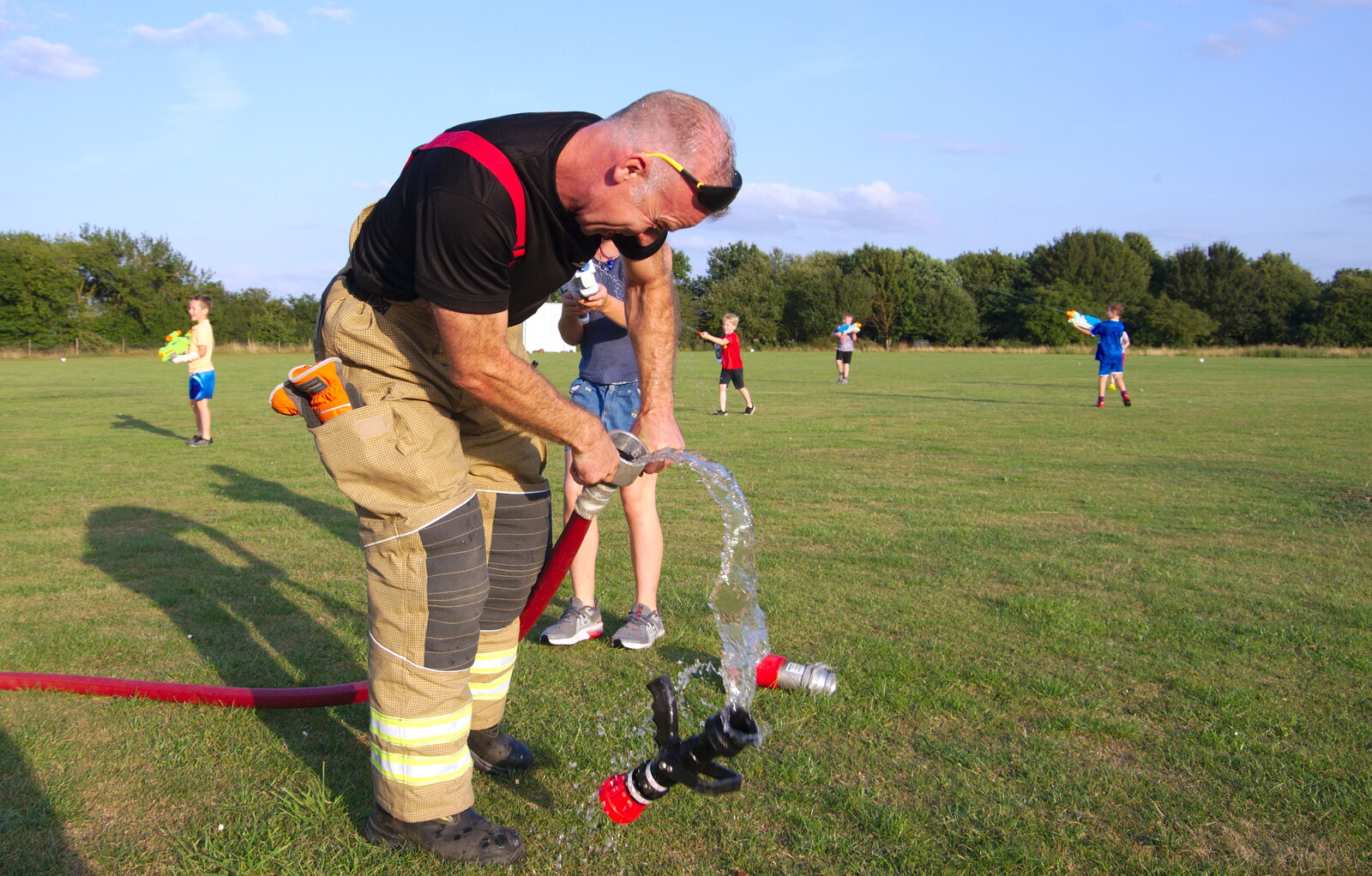 A fireman detatches the jet nozzle from A Water Fight with a Fire Engine, Eye Cricket Club, Suffolk - 5th August 2019