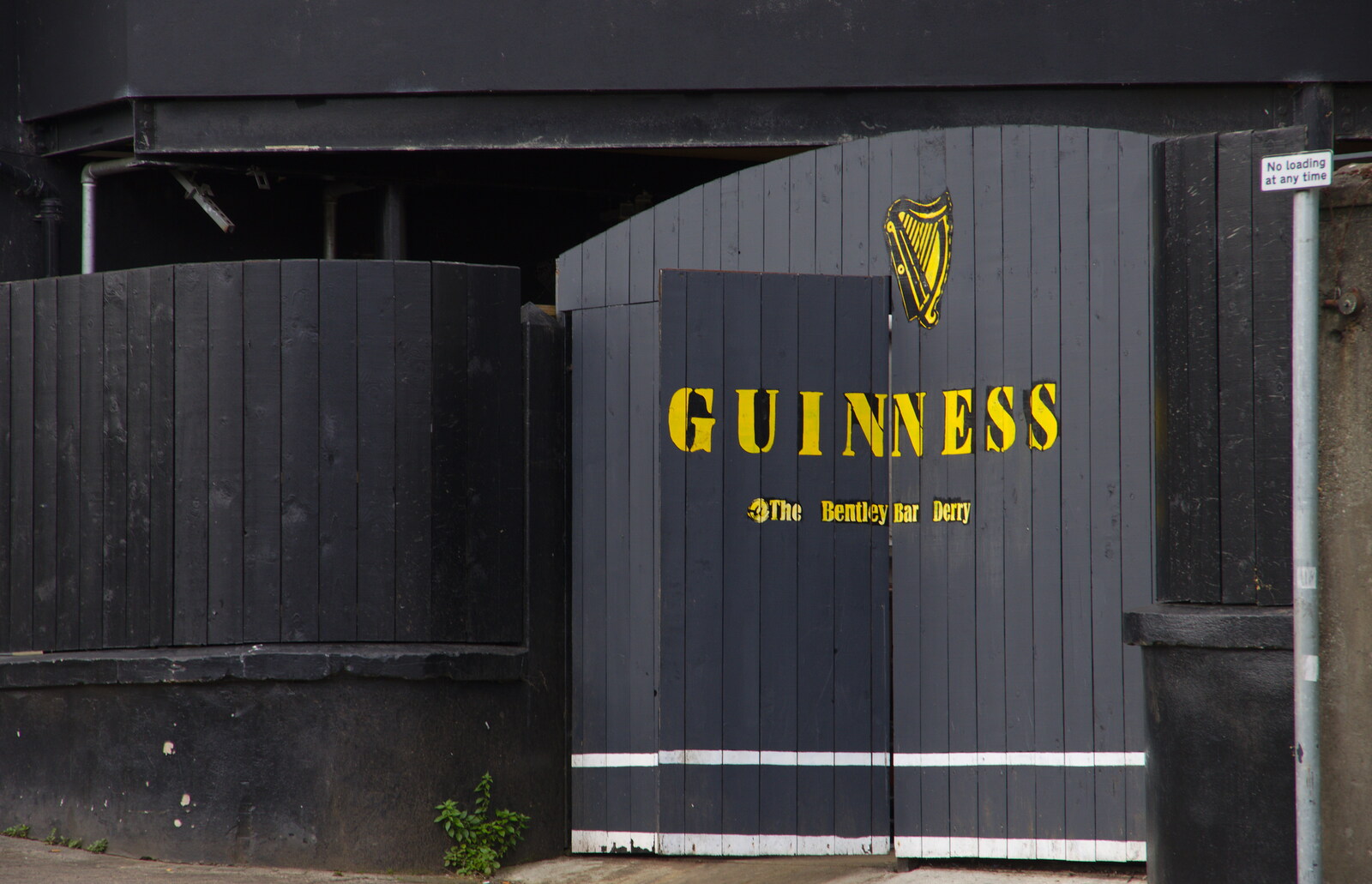 A yellow Guiness sign on the Bentley Bar's gate from A Day in Derry, County Londonderry, Northern Ireland - 15th August 2019