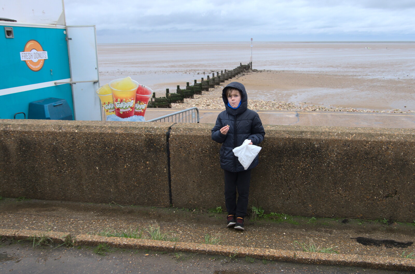 Harry eats a mini doughnut by the wall from A Postcard From Kings Lynn and "Sunny Hunny" Hunstanton, Norfolk - 31st October 2020