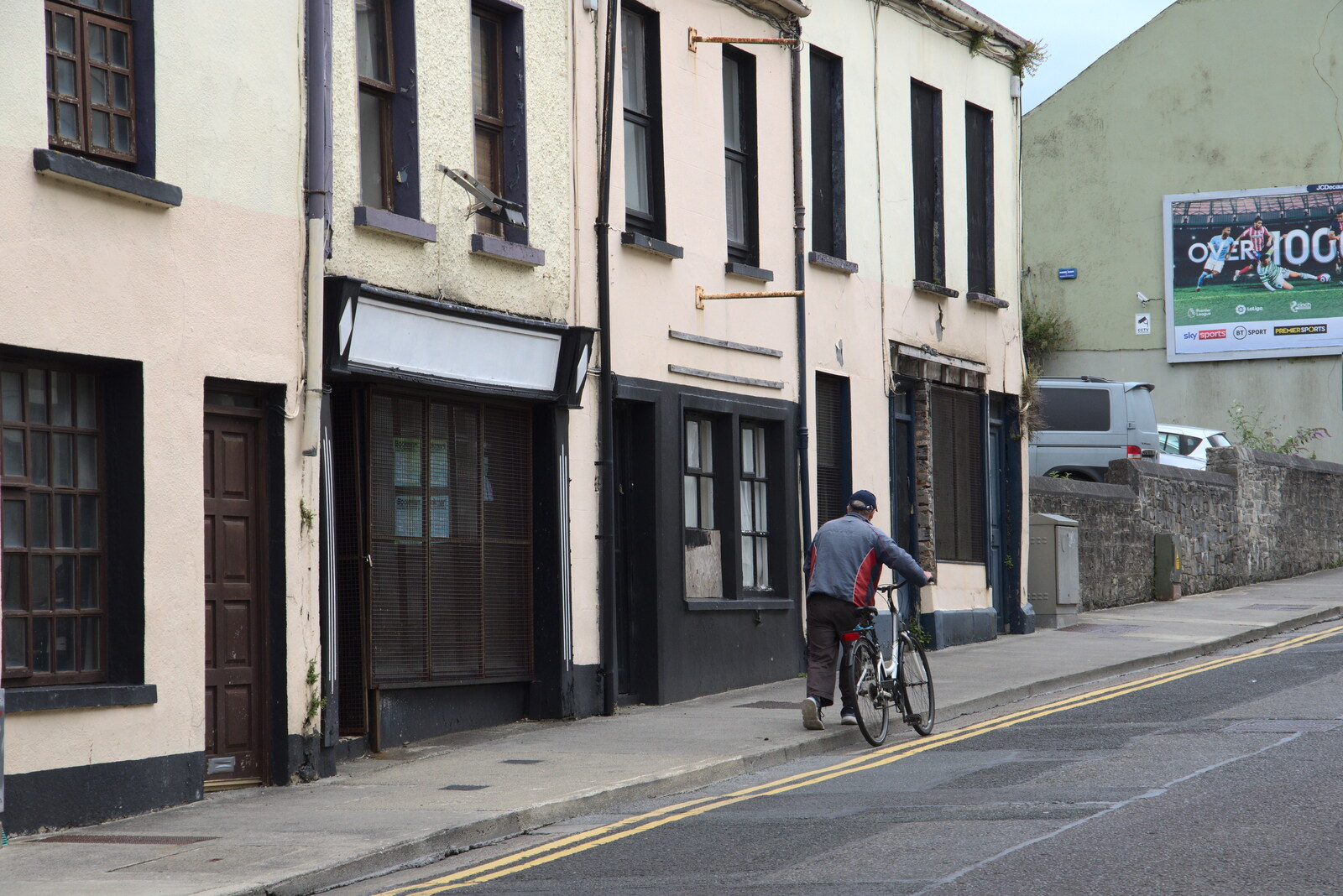 A Trip to Manorhamilton, County Leitrim, Ireland - 11th August 2021: Some dude pushes a bike up The Mall