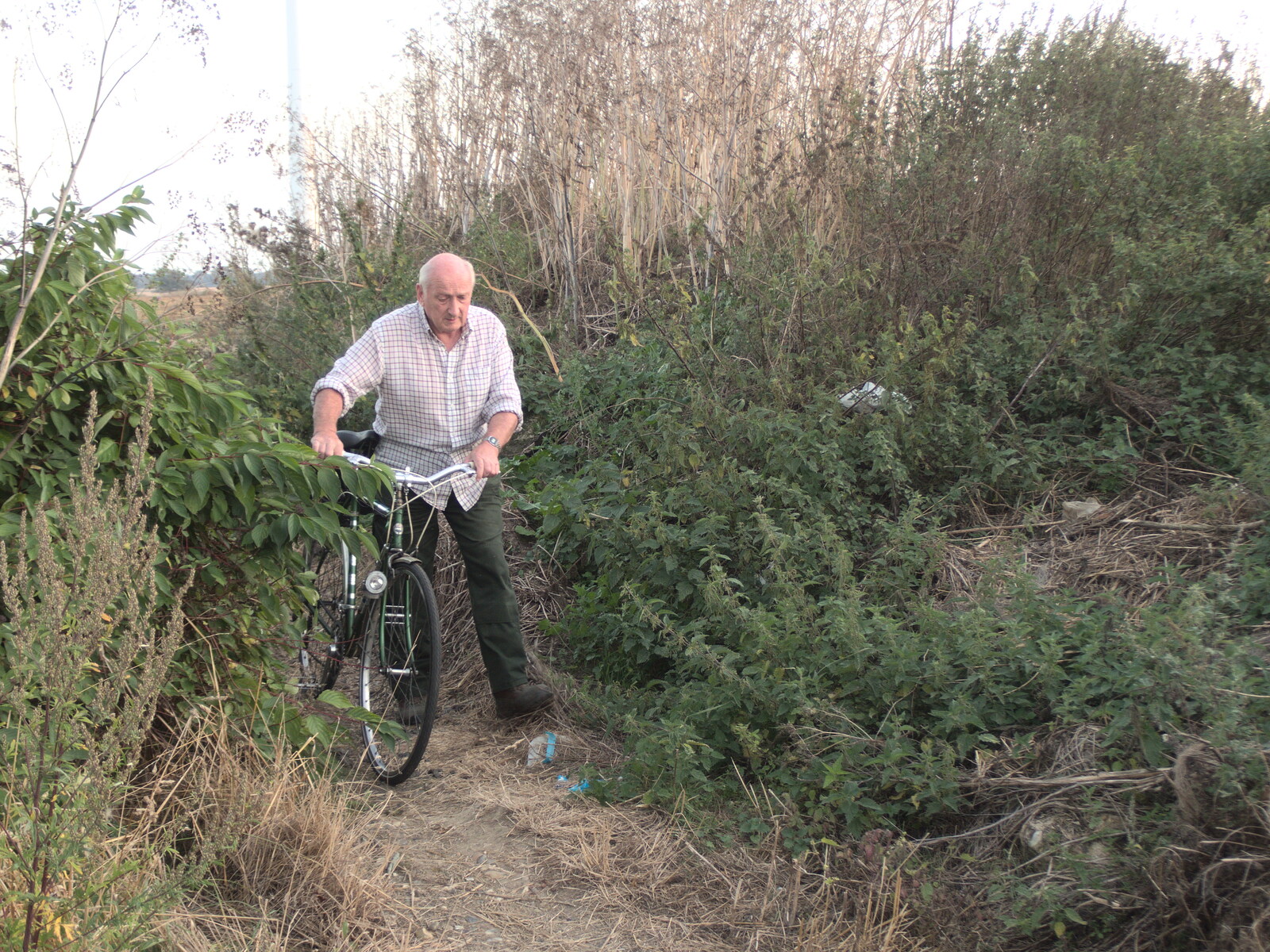 The Last Weavers Ever, Market Hill, Diss, Norfolk - 10th September 2021: Mick hauls his bike through the undergrowth