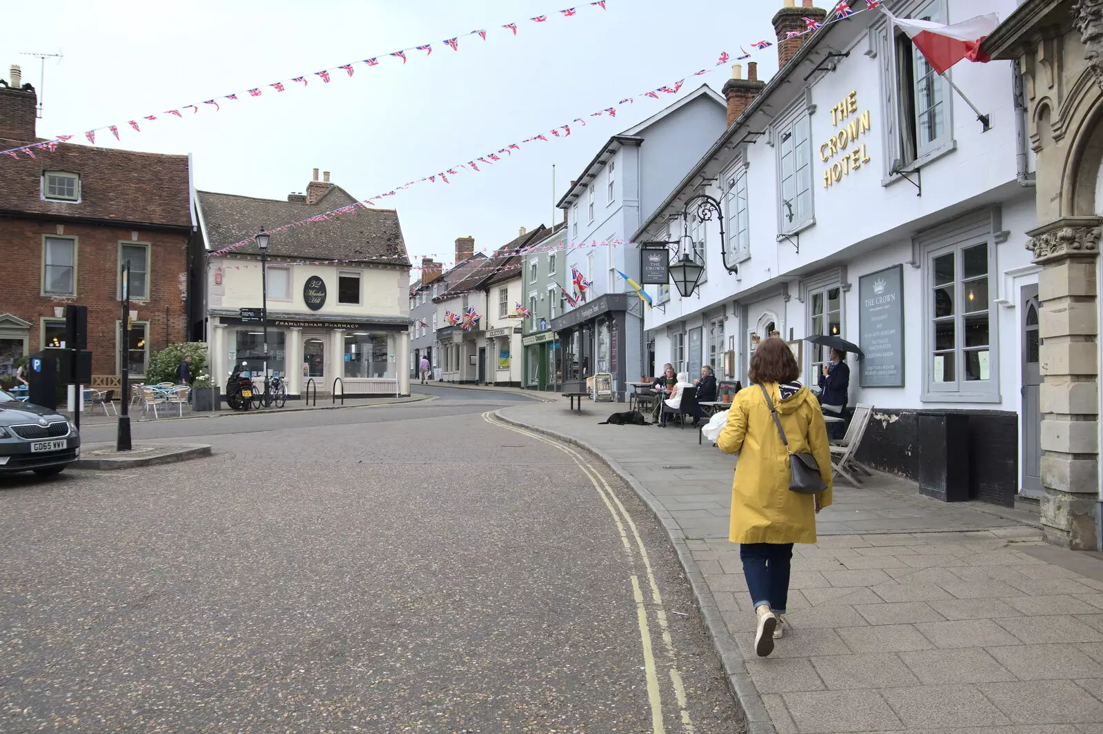 Isobel walks by the Crown Hotel, from On the Beach at Sea Palling, Norfolk - 8th May 2022