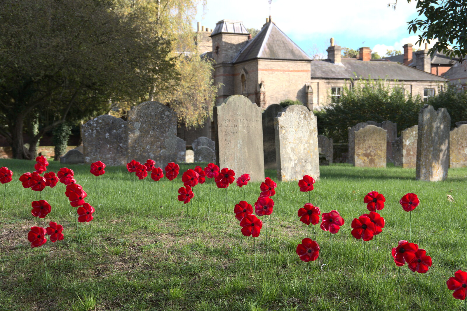 A Postcard from Flatford and Dedham, Suffolk and Essex, 9th November 2022: Artificial poppies wave around in the graveyard
