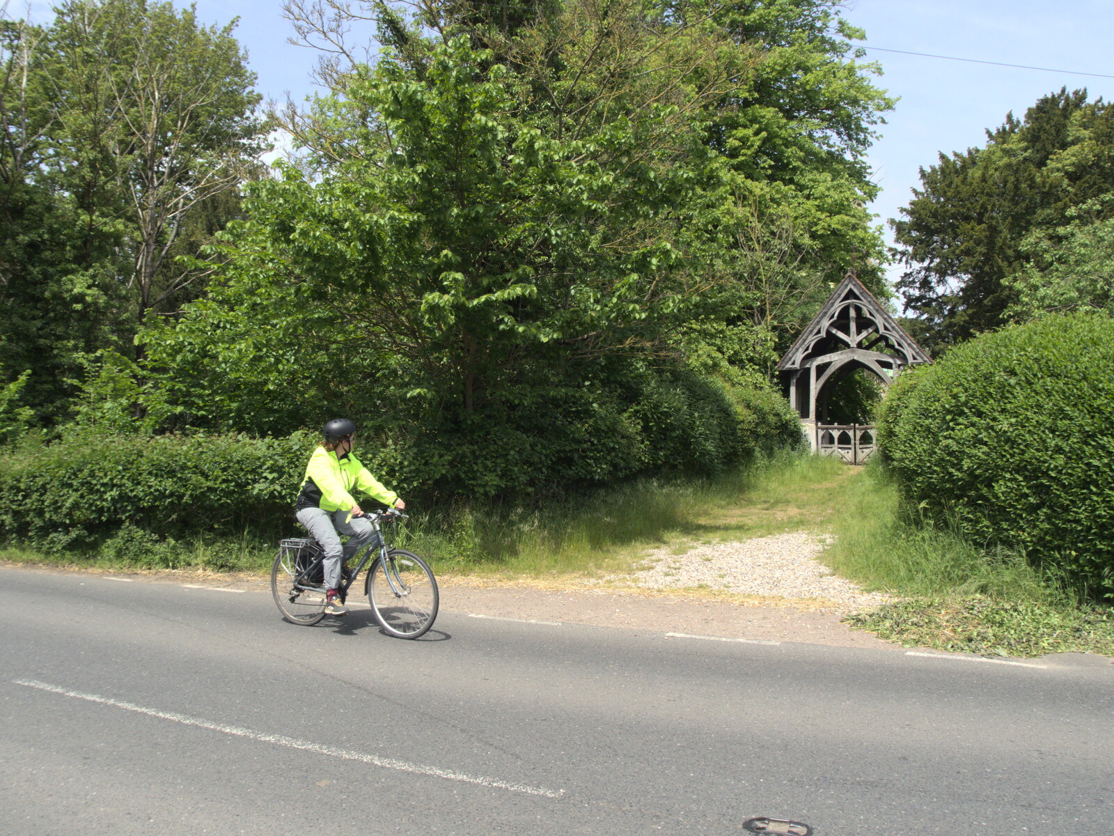Isobel cycles past the lych gate of Hoxne church from A Quest for the Fabled Swimming Spot, Hoxne, Suffolk - 29th May 2023