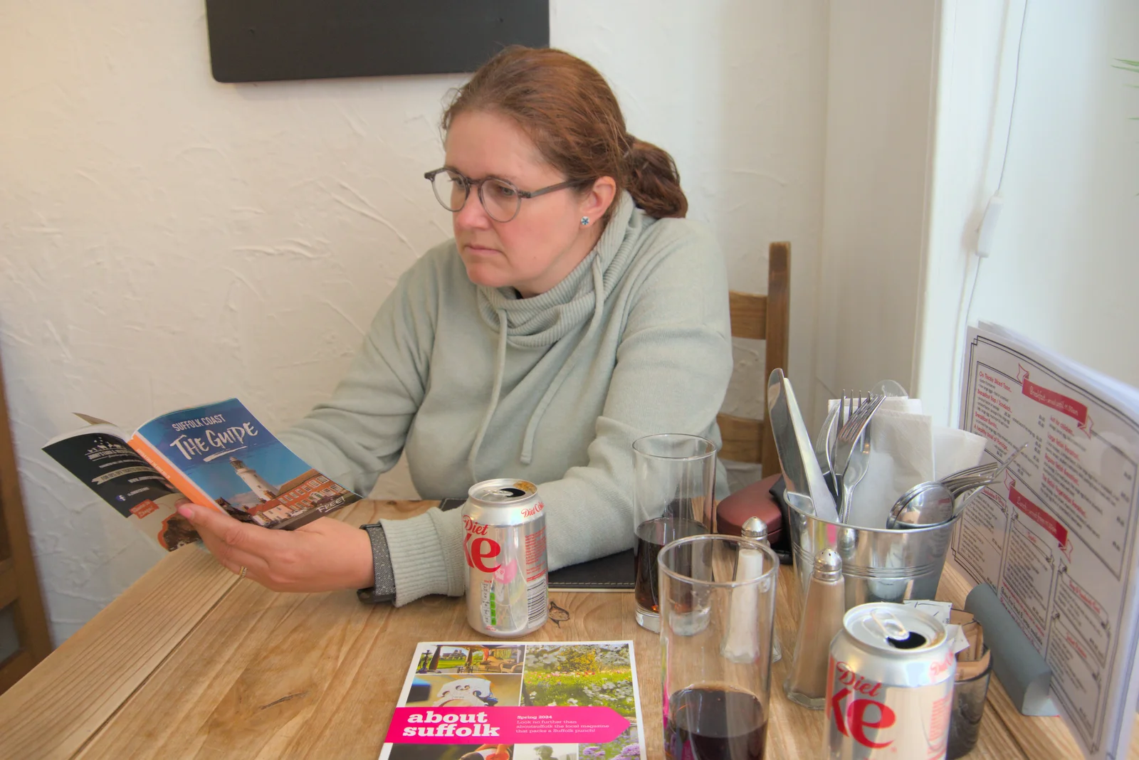 Isobel scopes out a guidebook in the café, from A Trip to Beccles, and the BSCC at The Greyhound, Botesdale, Suffolk - 23rd May 2024