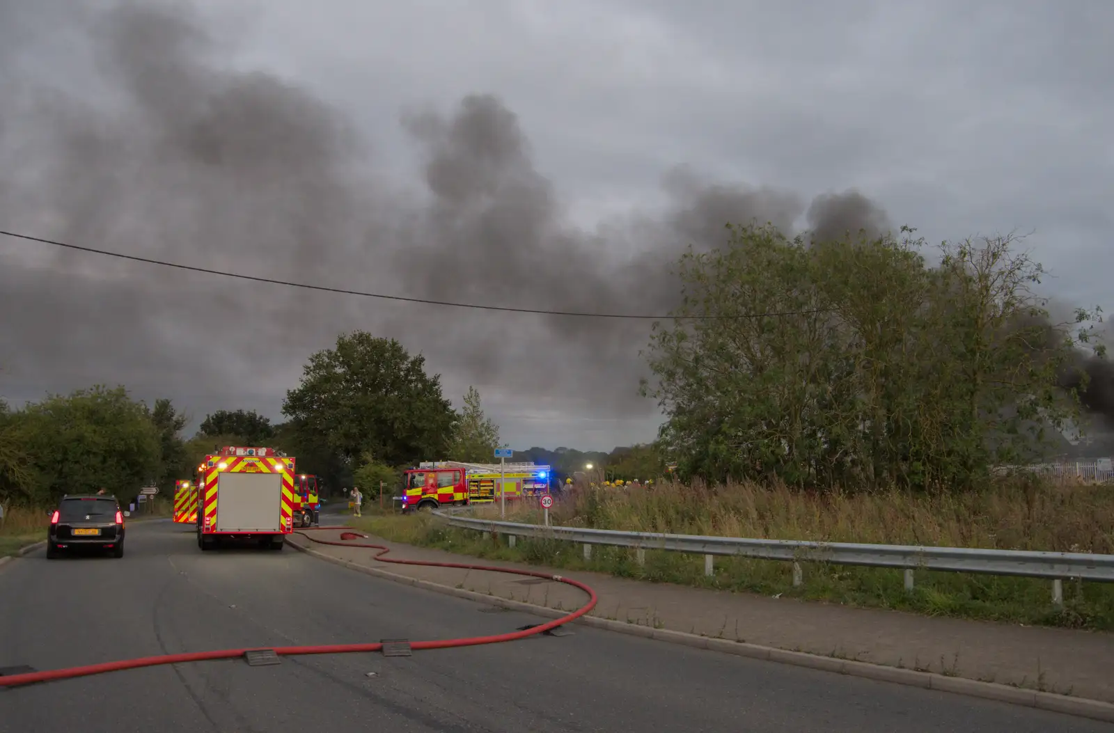 A hose snakes across the road, from A Major Fire at Suffolk Highways, Brome, Suffolk - 15th September 2024