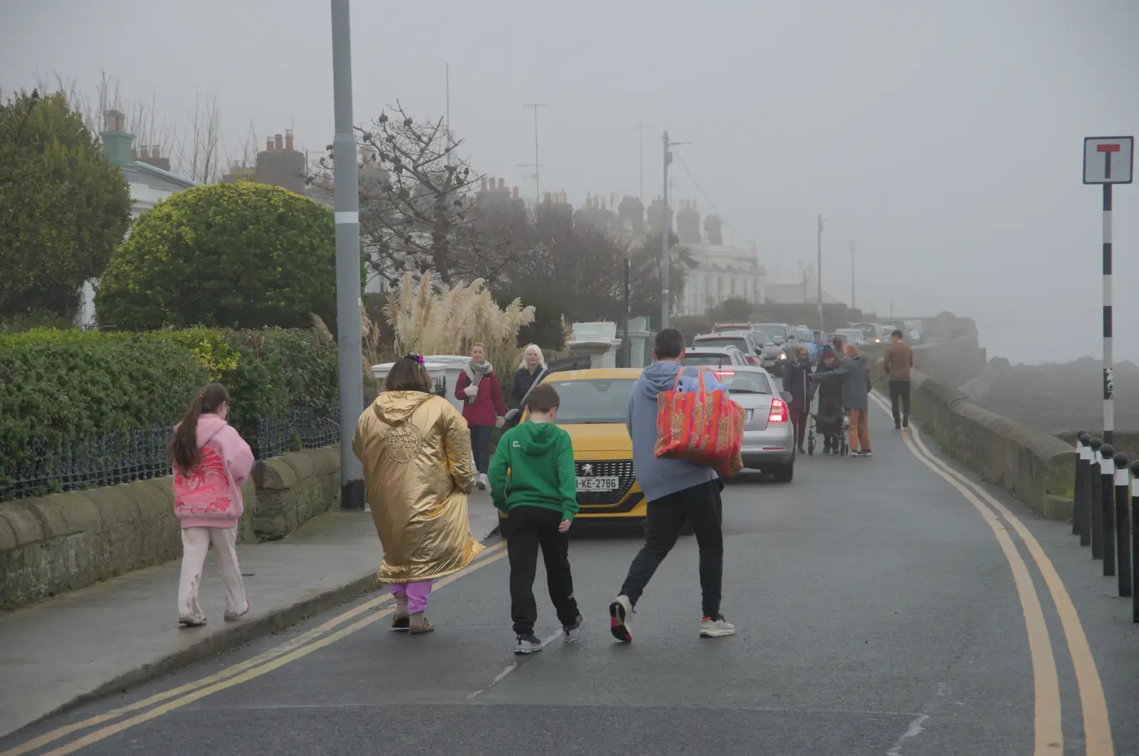 Someone wanders down the road in a gold Dryrobe, from St. Stephen's Day in Blackrock, County Dublin, Ireland - 26th December 2024