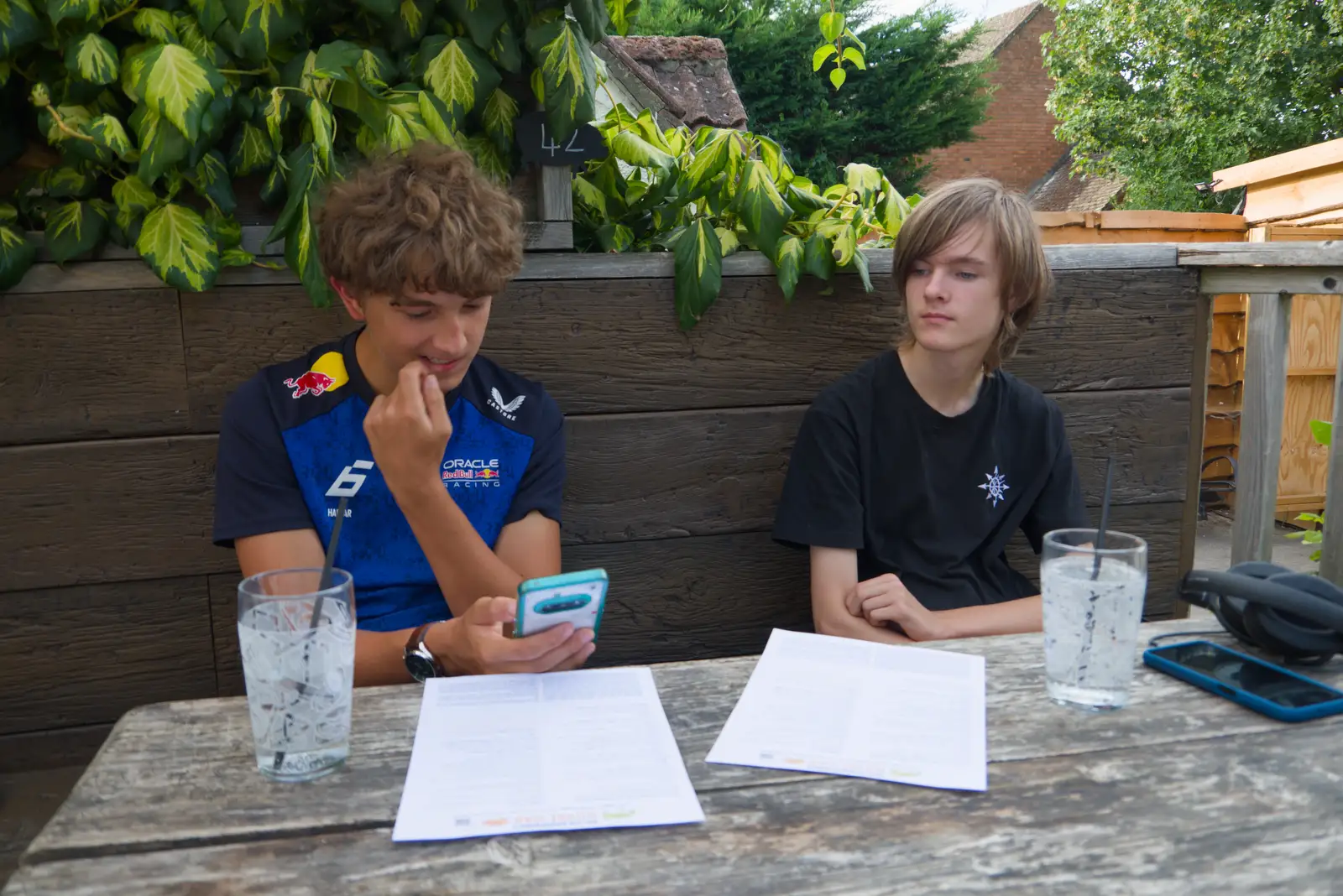 Elliot checks his phone as Harry scopes the menu, from Walking the Ridgeway: Chiseldon to Avebury, Wiltshire - 10th August 2026